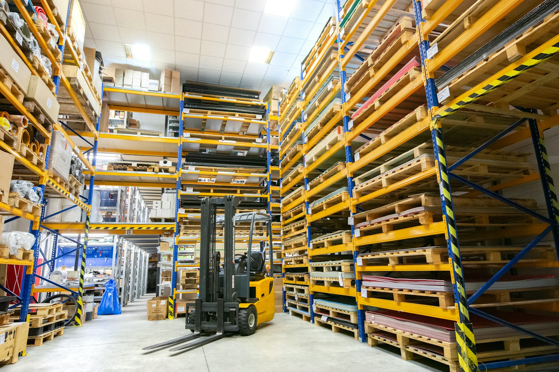 A photograph of a warehouse with a forklift truck in the middle.